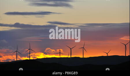 Windenergieanlagen in Meridian's West Wind Farm, drehen Sie langsam gegen eine Mid-Winter orange Sonnenuntergang Stockfoto