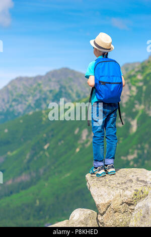 Ansicht von der Rückseite junge Reisende mit einem Rucksack steht auf einem Felsen und genießen die schöne Landschaft Stockfoto