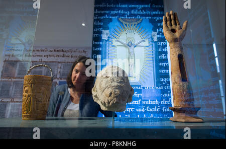 Merseburg, Deutschland. 12. Juli 2018. Eine wertvolle Schaufel für heilige Wasser (L-R) von Mailand, vor 980, ein Fragment eines Steinkopf von Köln oder Bonn, um 1015, und der Arm Reliquie des heiligen Laurentius, aus dem 15. Jahrhundert finden sich in der neuen Sonderausstellung "Thietmars Welt gesehen werden. Ein merseburger Bischof schreibt Geschichte" (Lit. "Thietmar der Welt. Ein Bischof von Merseburg schreibt Geschichte"). Die Ausstellung über Thietmar von Merseburg (975-1018) läuft vom 15. Juli bis zum 04. November 2018. Credit: Hendrik Schmidt/dpa-Zentralbild/ZB/dpa/Alamy leben Nachrichten Stockfoto