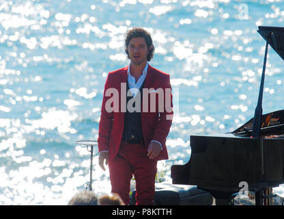 Newquay, Cornwall, England. 12. Juli 2018. Rosamunde Pilcher Schauspieler Manuel Mairhoffer spielt Klavier auf den Klippen, Filmen 'Meine Brüder Braut' Fistral Beach, UK, 12., Juli, 2018 Robert Taylor/Alamy Leben Nachrichten. Newquay, Cornwall, England. Credit: Robert Taylor/Alamy leben Nachrichten Stockfoto