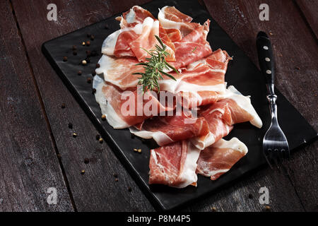 Italienische Prosciutto Crudo oder jamon mit Rosmarin. Rohen Schinken. Stockfoto