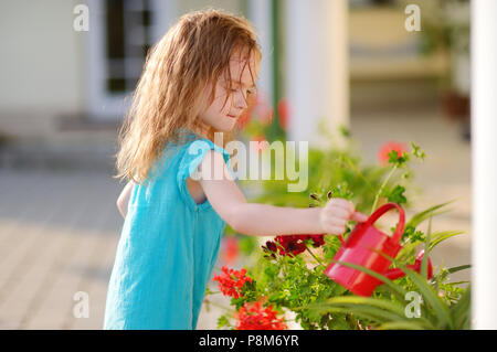 Süße kleine Mädchen Blumen gießen im Garten auf schönen Sommertag Stockfoto
