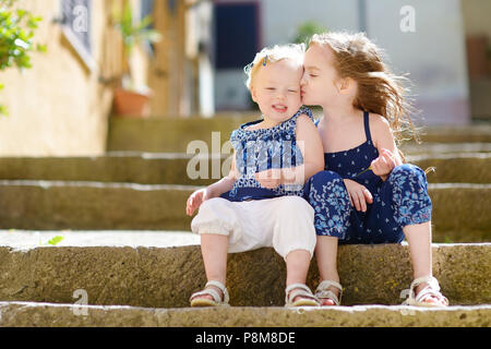 Zwei süße kleine Schwestern sitzen auf der Treppe in der italienischen Stadt Stockfoto