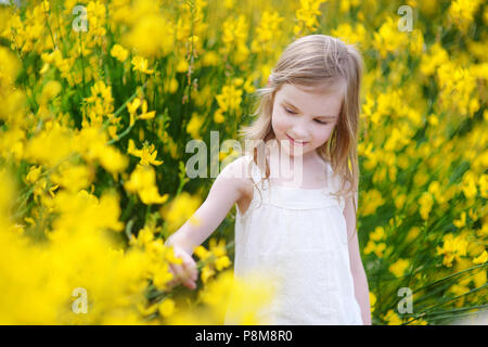 Adorable kleinen Mädchen in blühenden gelben Blumen Stockfoto