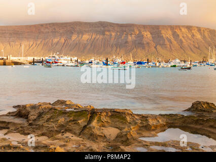Blick über die Marina auf der Insel La Graciosa bei Lanzarote im Hintergrund. Kanarische Inseln, Spanien Stockfoto