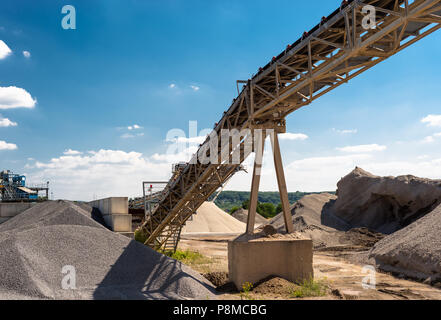 Förderband über Haufen von Kies auf blauen Himmel bei einem industriellen Zementwerk. Stockfoto