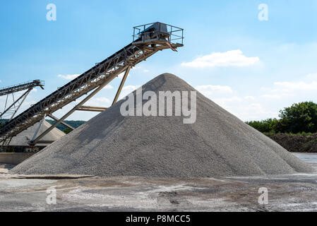 Förderband über Haufen von Kies auf blauen Himmel bei einem industriellen Zementwerk. Stockfoto