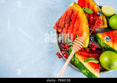 Sommer bbq Konzept, gegrillter Wassermelone mit Beeren, Minze, Limette und Honig, hellblauer Hintergrund Kopie Raum über Stockfoto