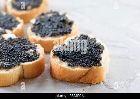 Teure leckere schwarze Kaviar Weißbrot sandwich Snack auf einem hölzernen Platte Stockfoto