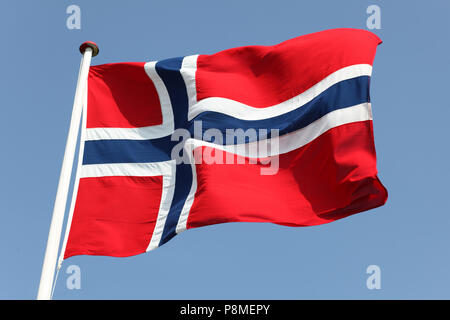 Die norwegische Flagge auf Fahnenmast gegen den blauen Himmel. Stockfoto