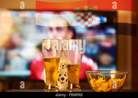 Double Exposure der kroatischen Flagge und zwei Gläser Bier vor dem Fernseher Fußball spielen Stockfoto