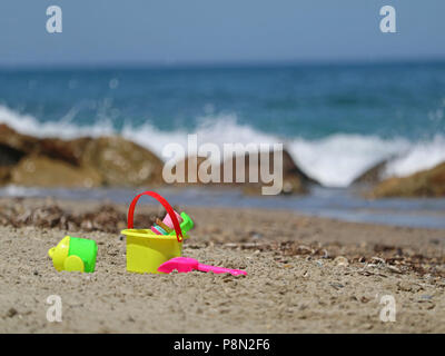 Buntes Spielzeug, Eimer und Schaufel, in Sand mit Meerblick Stockfoto