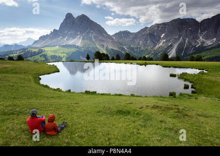 Mutter und Sohn in der Nähe des Wackerer See mit erstaunlichen Reflexion sitzend, im Hintergrund der Sass de Peiterkofel, Dolomiten, Italien, Südtirol, Bozen Stockfoto