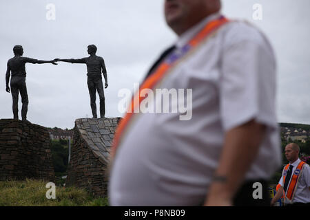 Eine Orange um Parade übergibt die "Hände über der Kluft" Statue in Londonderry als Teil der jährlichen Zwölften Juli feiern, Kennzeichnung der Sieg von König William III. Sieg über James II. in der Schlacht von Boyne im Jahre 1690. Bild Datum: Donnerstag, 12. Juli 2018. Siehe PA Geschichte ULSTER Paraden Londonderry. Photo Credit: Brian Gesetzlosen/PA-Kabel Stockfoto