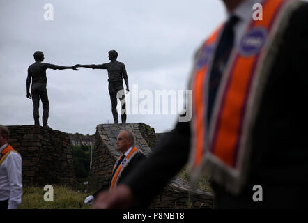 Eine Orange um Parade übergibt die "Hände über der Kluft" Statue in Londonderry als Teil der jährlichen Zwölften Juli feiern, Kennzeichnung der Sieg von König William III. Sieg über James II. in der Schlacht von Boyne im Jahre 1690. Bild Datum: Donnerstag, 12. Juli 2018. Siehe PA Geschichte ULSTER Paraden Londonderry. Photo Credit: Brian Gesetzlosen/PA-Kabel Stockfoto