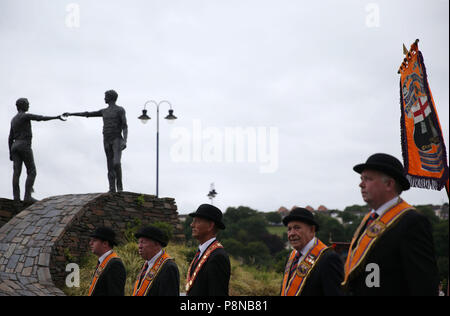 Eine Orange um Parade übergibt die "Hände über der Kluft" Statue in Londonderry als Teil der jährlichen Zwölften Juli feiern, Kennzeichnung der Sieg von König William III. Sieg über James II. in der Schlacht von Boyne im Jahre 1690. Bild Datum: Donnerstag, 12. Juli 2018. Siehe PA Geschichte ULSTER Paraden Londonderry. Photo Credit: Brian Gesetzlosen/PA-Kabel Stockfoto