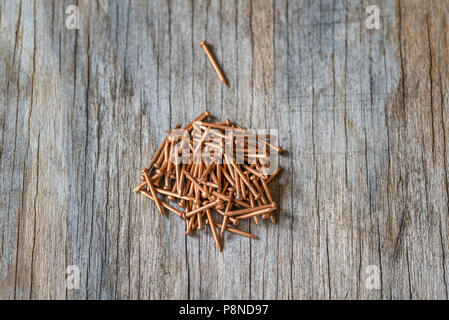 Nahaufnahme von einer Gruppe von Bronze Nägel auf eine holzmaserung Hintergrund. Stockfoto