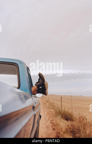 Schuß von Frau entspannen in einem Auto auf Road Trip. Weibliche Füße aus dem Fenster. Stockfoto