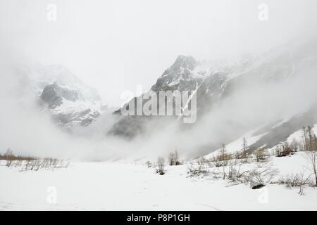 Dramatische Atmosphäre im Frühling in den französischen Alpen mit dem Schnee schmelzen und tief hängenden Wolken Stockfoto