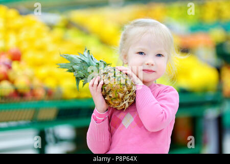 Süße kleine Mädchen, dass eine Ananas in einem Kaufhaus oder Supermarkt. Stockfoto