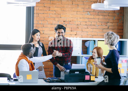 Fröhlich afrikanische Kerl ist die Hand zu hinduistischen Mann seine freundliche Behandlung an Kollegen zu zeigen. enge Partner Stockfoto