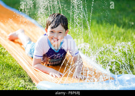 Junge gleiten auf Slip n Slide in Hof im Sommer. Photo Credit: Katherine Penn Stockfoto