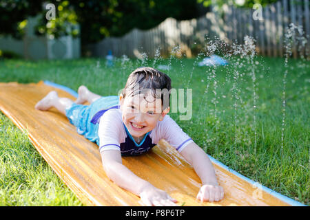 Junge gleiten auf Slip n Slide in Hof im Sommer. Photo Credit: Katherine Penn Stockfoto