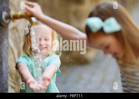 Zwei Schwestern Spaß mit Trinkwasser Brunnen in Italien an warmen und sonnigen Sommer Tag Stockfoto