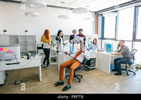 Afrikanische Büroangestellter ist ein wichtiges Gespräch auf dem Smartphone bei der Arbeit. Die Einzelheiten der Begegnung mit Kunden am Telefon Stockfoto