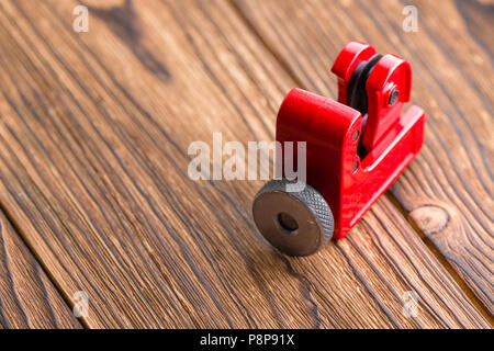 Nahaufnahme eines Red Steel pipe Cutter ein rustikales Holz mit Kopie Raum gesehen hohen Winkel mit dem Rad zum Schneiden der Sanitär Rohre oder Schläuche Stockfoto