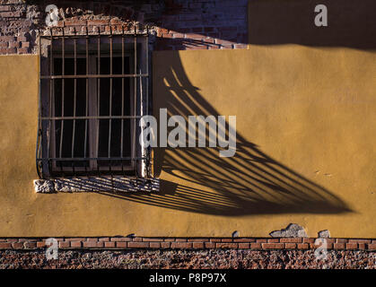 Am späten Nachmittag Sonne werfen einen langen Schatten auf das schmiedeeiserne über das Fenster Stockfoto