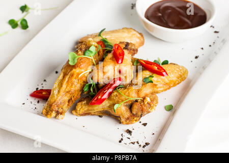 Gegrilltes gebackenes Huhn Flügel mit Chili und heiße Soße auf weiße Platte Stockfoto