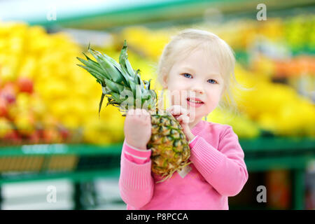 Süße kleine Mädchen, dass eine Ananas in einem Kaufhaus oder Supermarkt. Stockfoto