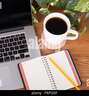 Hohen winkel Blick auf ein leeres Notizbuch und Bleistift mit einem Laptop auf einem Desktop Stockfoto