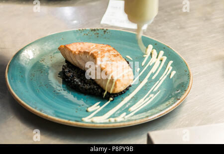 Gegrillter Lachs auf einer Platte positioniert mit schwarzen Bulgur - Kochen mit Dressing Stockfoto