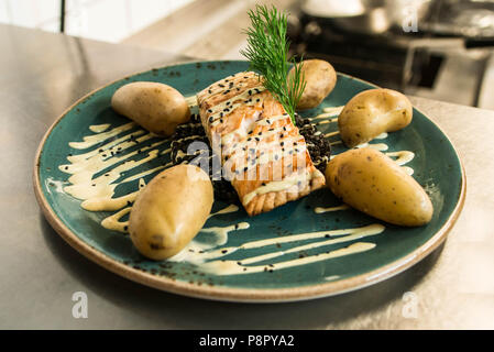 Gegrillter Lachs auf einer Platte mit einem schwarzen Bulgur und mit gekochten Kartoffeln für ein Abendessen arrangiert platziert Stockfoto