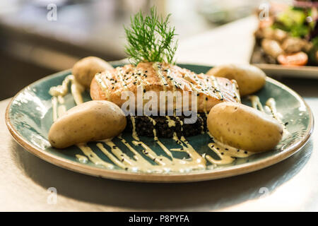 Gegrillter Lachs auf einer Platte mit einem schwarzen Bulgur und mit gekochten Kartoffeln für ein Abendessen arrangiert platziert Stockfoto