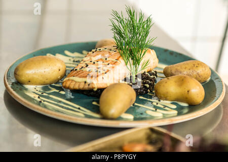 Gegrillter Lachs auf einer Platte mit einem schwarzen Bulgur und mit gekochten Kartoffeln für ein Abendessen arrangiert platziert Stockfoto