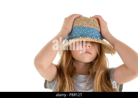 Lustige kleine Mädchen versteckt sich unter ihr straw hat die Krone nach unten drücken auf dem Kopf mit den Händen in der Verlegenheit isoliert auf weißem Stockfoto