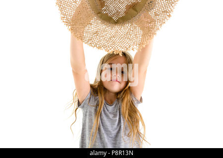 Glückliche kleine Mädchen mit langen blonden Haaren jubeln und winken sie Stroh Sonnenhut über ihren Kopf mit einem Lächeln isoliert auf weißem Stockfoto