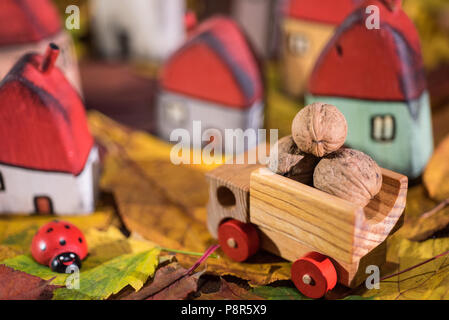 Spielplatz für Kinder, Anordnung von bemalten Spielzeug Holzhäuser, Lkw mit Muttern, Marienkäfer auf der Blätter im Herbst. Kindheit Konzept Stockfoto