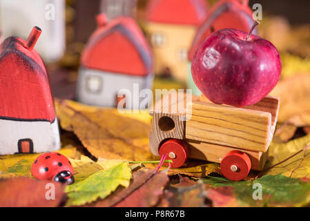 Spielplatz für Kinder, Anordnung von bemalten Spielzeug Holzhäuser, Lkw mit einem Apple, Marienkäfer auf der Blätter im Herbst. Kindheit Konzept Stockfoto