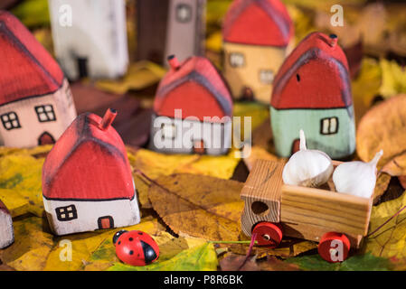 Spielplatz für Kinder, Anordnung von bemalten Spielzeug Holzhäuser, Lkw mit Knoblauch, Marienkäfer auf der Blätter im Herbst. Kindheit Konzept Stockfoto