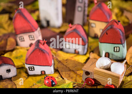 Spielplatz für Kinder, Anordnung von bemalten Spielzeug Holzhäuser, Lkw mit Knoblauch, Marienkäfer auf der Blätter im Herbst. Kindheit Konzept Stockfoto