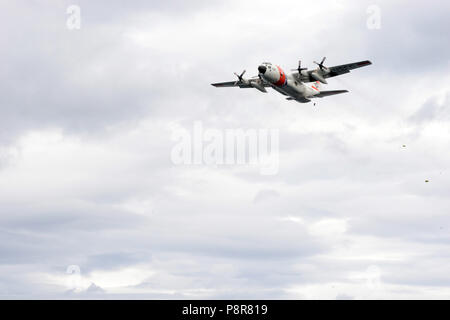 Ein Coast Guard Air Station Kodiak HC-130 Hercules-transportflugzeuge Crew fällt in das Wasser zum Abrufen durch Aids zur Navigation Team Kodiak Crew Mitglieder in Kodiak, Alaska, 10. Juli 2018. Drop Training ist zu fallen Lieferungen simulieren die Überlebenden bedeutete. U.S. Coast Guard Foto von Petty Officer 3. Klasse Lauren Dean. Stockfoto