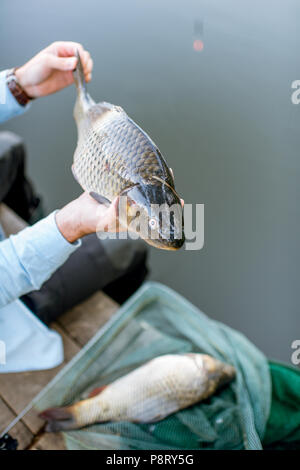 Fischer holding Fisch beim Angeln auf dem See Stockfoto