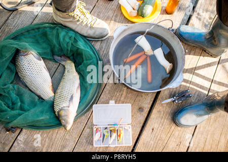 Fischer's Picknick mit Fisch, Suppe und Angeln packt auf der hölzernen Pier Stockfoto