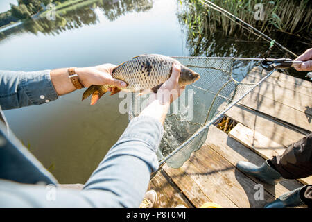 Fischer, erwischt zu Fisch aus dem fischernetz in der Nähe des Sees am Morgen Stockfoto