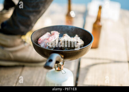 Braten zwei Fische steakes am Brenner beim Picknick mit Bier und Angeln geht im Freien Stockfoto