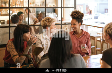 Junge weibliche Freunde zusammen lachen über Getränke in einem Bistro